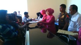 Ketua Bhayangkari Polres Sampang (Wulan Budhi Wardiman), didampingi Kapolres Sampang AKBP Budhi Wardiman dan Kepala Dispenduk Capil Kab. Sampang (Ali Wafa), saat memberikan akte kelahiran kepada warga.