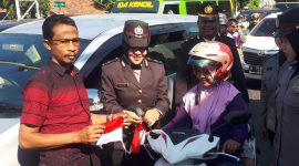 Ketua Persatuan Wartawan Sampang Ahmad Juma'adi (kiri) bersama Polwan Polres Sampang saat memasang bendera mini ke kendaraan yang dikendarai salah satu pengendara motor.