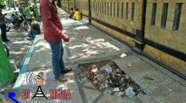 Salah satu pejalan kaki saat melihat kondisi trotoar berlubang dipenuhi tumpukan sampah.