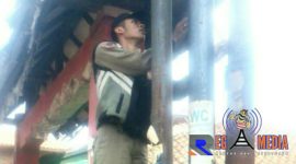 Anggota Satpol PP mencoba menurunkan APK yang berada di tiang tiang listrik di pinggir jalan.