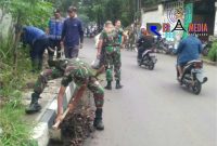Tampak anggota TNI dan warga tengah bergotong royong membersihkan rerumputan dan sampah.