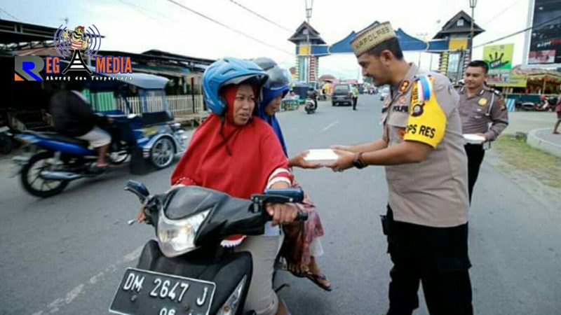 Kapolres Bone Bolango (AKBP Desmont Harjendro) tengah membagikan takjil kepada pengendara yang melintas.