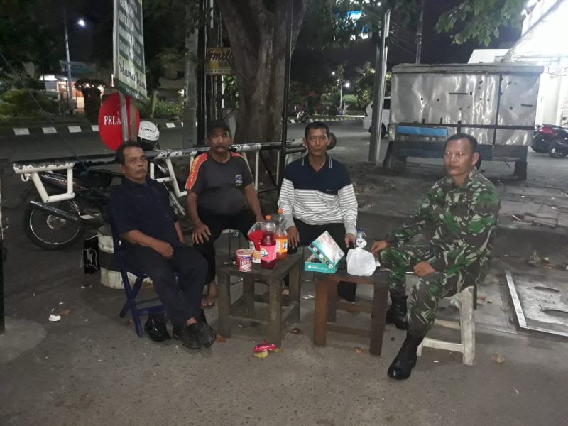 Terlihat anggota TNI tengah duduk santai bersama warga sembari menjaga keamanan.