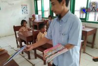 Salah satu guru SDN Bapelle 1 saat membagikan buku pelajaran sebelum dimulainya kegaiatan belajar mengajar.