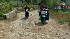 Terlihat beberapa pengendara melintasi jalan poros Desa Torjunan yang rusak.