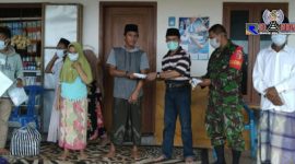 Kepala Desa Gunung Rancak (Moh. Juhar) tengah memberikan masker kepada warganya. 