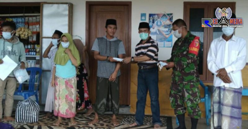 Kepala Desa Gunung Rancak (Moh. Juhar) tengah memberikan masker kepada warganya. 