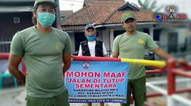 Isolasi mandiri lingkungan; petugas Linmas memasang plang penutup jalan. 