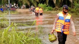 Salah satu personel brimob terlihat tengah membantu membawakan peralatan dapur warga. 