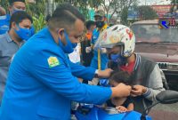 Ketua DPD KNPI Provinsi Aceh (Wahyu Saputra) saat membagikan masker kepada seorang anak pengendara motor. 