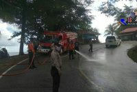 Terlihat mobil pemadam kebakaran dari BPBD Aceh Selatan melakukan pembersihan ruas jalan dari tumpahan minyak.