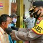 Kapolres Bangkalan (AKBP Rama Samtama Putra) saat memakaikan masker pada warga.