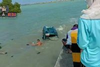 Terlihat salah satu warga  mencoba mengevakuasi para penumpang mobil carry yang terjun kelaut. 