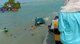 Terlihat salah satu warga  mencoba mengevakuasi para penumpang mobil carry yang terjun kelaut. 