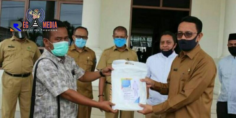 Sekda Aceh Selatan (H. Nasjuddin) saat menerima bantuan APD dari dua pengusaha yang diwakilkan tokoh masyarakat. 