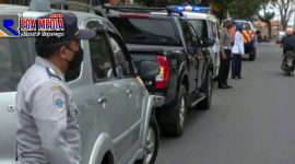 Terlihat petugas dari Dishub dan kepolisian berada di pinggir barisan mobil yang terparkir.