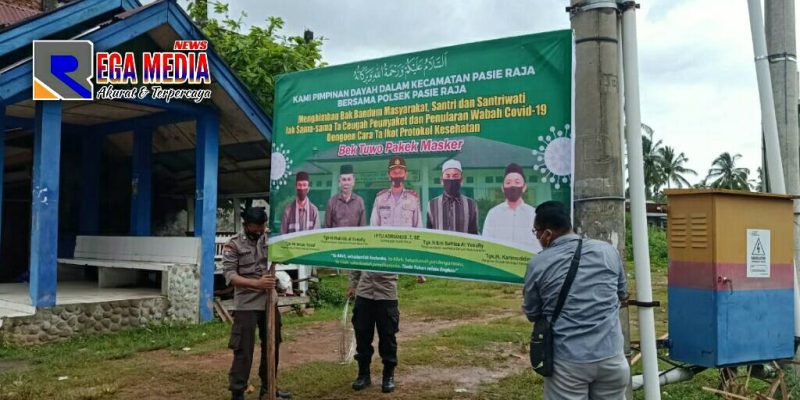 Anggota Polsek Pasie Raja terlihat tengah memasang baliho bertuliskan kalimat imbauan prokes.