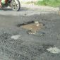 Kondisi kubangan air di jalan berlubang di lintas jalan raya Sampang-Ketapang.