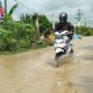 Tampak pengendara sepeda motor menerobos genangan air di sepanjang jalan raya Kamoning-Sampang.