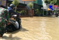 Babinsa Koramil 0828/01 Sampang saat bantu warga yang sepeda motornya mogok ditengah banjir.