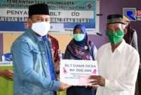 Sekda Gorontalo Utara (Ridwan Yasin) saat menyerahkan BLT Dana Desa kepada salah satu KPM.