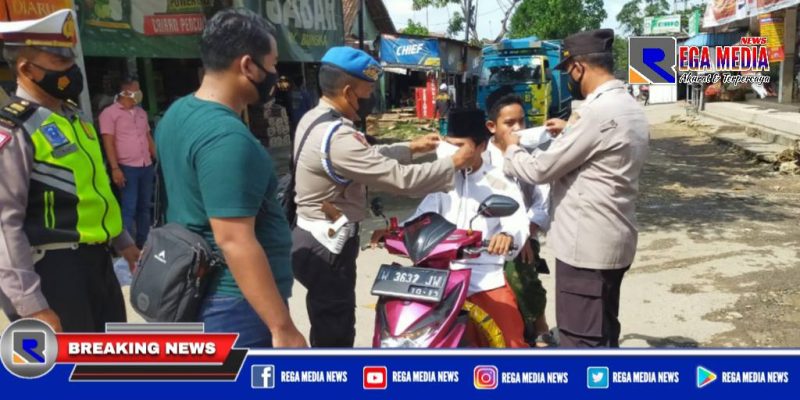 Anggota Polres Sampang saat mengenakan masker kepada pengendara yang  terjaring penyekatan dan operasi yustisi prokes.