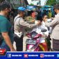 Anggota Polres Sampang saat mengenakan masker kepada pengendara yang  terjaring penyekatan dan operasi yustisi prokes.
