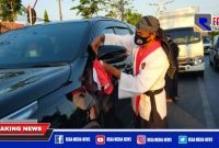 Ketua umum perguruan pencak silat Surban Putih saat mengikatkan bendera merah putih ke kendaraan.