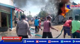 Terlihat petugas kepolisian dan warga mencoba memadamkan api yang membesar.