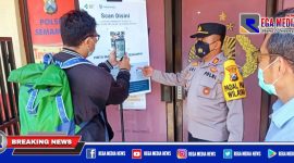 Caption: Kapolsek Semampir (AKP Ari Bayuaji) memberikan arahan menggunakan barcode aplikasi pedulilindungi.