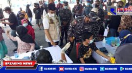 Caption: tampak Bupati Bangkalan tengah mengecek data warga yang mengikuti serbuan vaksin Koarmada II TNI AL.