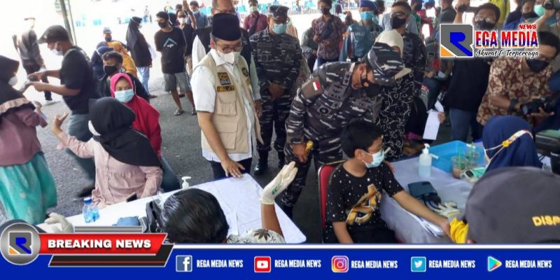 Caption: tampak Bupati Bangkalan tengah mengecek data warga yang mengikuti serbuan vaksin Koarmada II TNI AL.