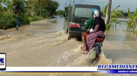 Caption: tampak pengendara menerobos genangan banjir di ruas jalan raya Desa Kamoning - Pangilen, Sampang.