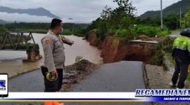 Caption: personil Polsek Suwawa saat memasang garis polisi di jalan Muchlis Rahim, Dusun III Desa Bulontala Timur, Kecamatan Suwawa Selatan, Bone Bolango, Gorontalo, yang amblas.