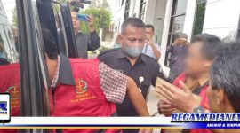 Caption: Camat dan Kepala Desa Tanjung Bumi hendak masuk ke mobil tahanan Kejaksaan Negeri Bangkalan.