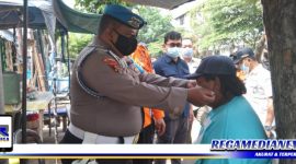 Caption: anggota Provost Polres Pelabuhan Tanjung Perak saat membagikan masker kepada warga.