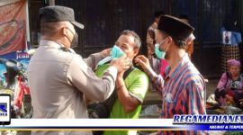 Caption: anggota Polsek Omben saat membagikan masker kepada pengunjung pasar, (Dok. Humas Polres Sampang).