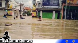 Caption: tampak sejumlah warga menerobos genangan banjir, (dok. red regamedianews).