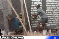 Caption: Satgas TMMD bersama warga tampak melakukan pengerjaan plaster dinding ruang guru SDN Pasarenan 2, (dok. regamedianews).
