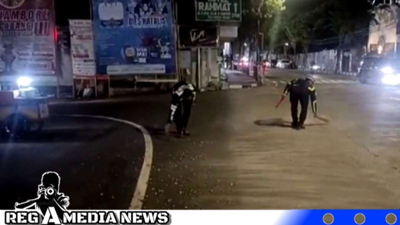 Caption: anggota Satlantas Polres Sampang membersihkan batu krikil yang berceceran di simpang empat monumen Jl.Trunojoyo, (dok. regamedianews). 