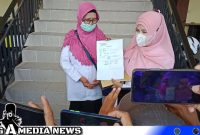 Caption: dua orang guru korban dugaan pelecehan seksual oknum Kepsek, tunjukkan surat tanda terima laporan polisi, (dok. regamedianews). 