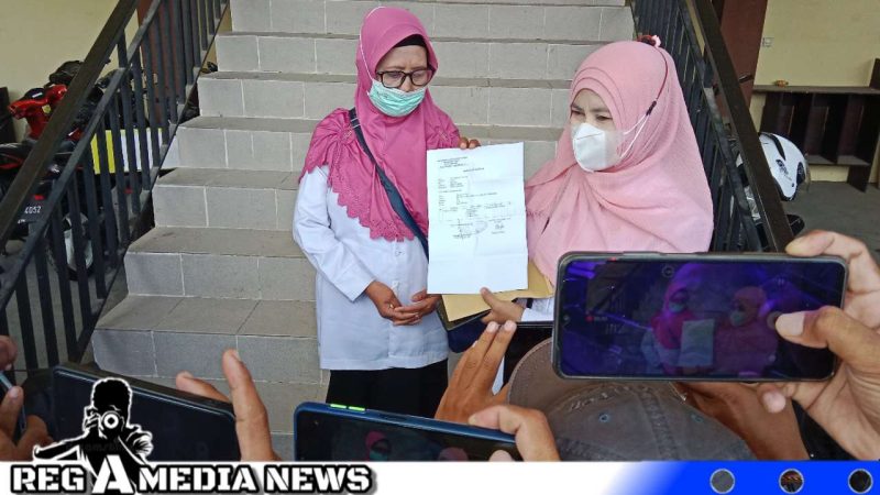 Caption: dua orang guru korban dugaan pelecehan seksual oknum Kepsek, tunjukkan surat tanda terima laporan polisi, (dok. regamedianews). 
