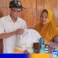 Caption: PJ Kepala Desa Rongdalam distribusikan langsung bantuan pangan nasional kepada keluarga penerima manfaat, (dok. regamedianews). 