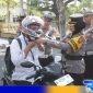 Caption: Kasat Lantas dampingi Wakapolres Sampang terapkan pemakaian helm yang benar kepada pengendara, (dok. Humas Polri). 