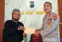 Caption: Kapolsek Omben (Iptu Sujinarto) saat menyerahkan surat izin keramaian kepada ketua panitia pelaksana haul, di ruang kerjanya, (dok. regamedianews). 