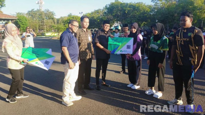 Caption: Bupati Sumenep didampingi Kepala BPJS Ketenagakerjaan Sumenep menyerahkan kartu kepesertaan kepada atlet KONI secara simbolis. 