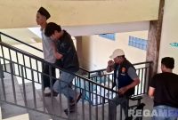 Caption: Kasat Reskrim Polres Sampang dan anggotanya, saat menggiring satu pelaku pembacokan (peci hitam) ke ruangan penyidik. 