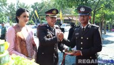 Caption: didampingi istri, Kapolres Bangkalan AKBP Hendro Sukmono berikan potongan tumpeng kepada anggotanya saat momen Hari Bhayangkara ke-79. 