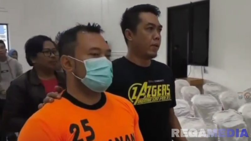 Caption: inisial ZA, tersangka penganiayaan kurir ekspedisi tampak memakai baju tahanan dan dikawal anggota Satreskrim Polres Pamekasan, (dok. regamedianews). 