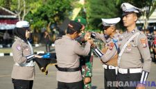 Caption: Kapolres Sampang AKBP Hartono pasang pita kepada personel TNI, saat apel Operasi Patuh Semeru 2025, (sumber foto: Humas Polres Sampang). 